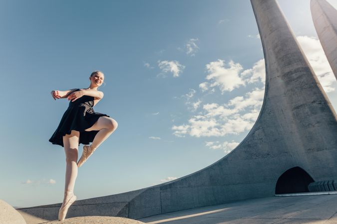 Female dancer balancing on one toe in pointe shoes on a rock