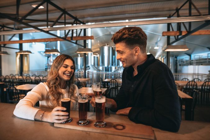 Cheerful couple sitting at bar table and enjoying alcoholic beverages