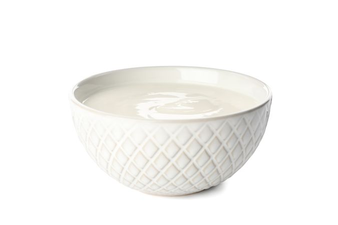 Bowl with cream yogurt isolated on light background