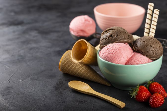 Bowl with Neapolitan ice cream on dark background.