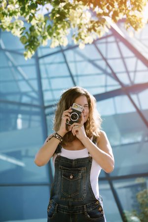 Creative woman taking photo on camera in sunny day