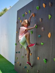 Cheerful boy climbing rock wall