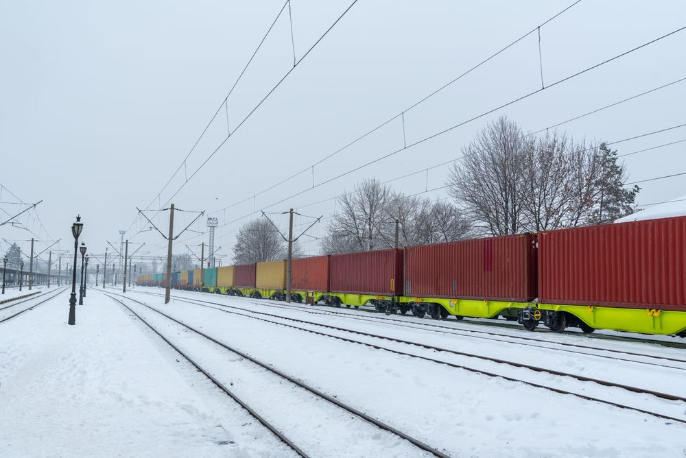 Freight train with multiple cargo containers passing through Suceava city train station, Romania