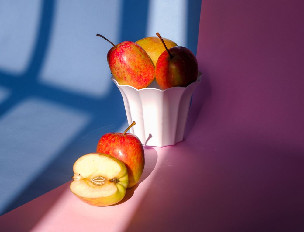 Photo of an apple in a container on a pink and blue background