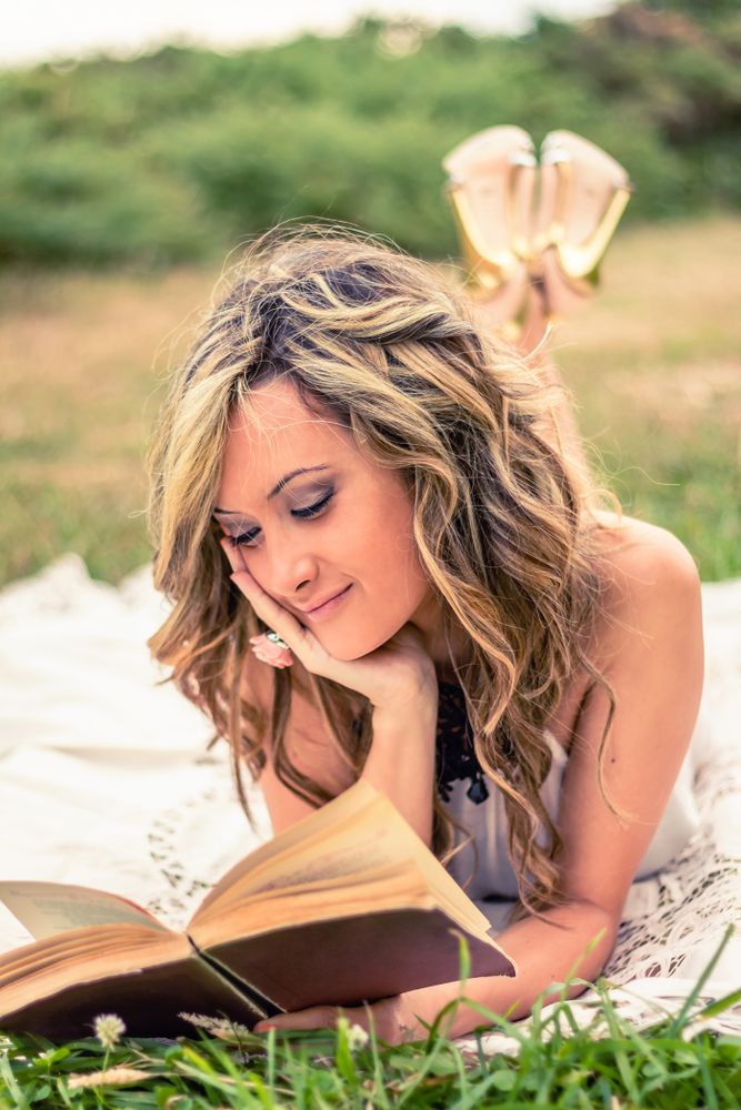 Romantic woman reading a book lying down outdoors