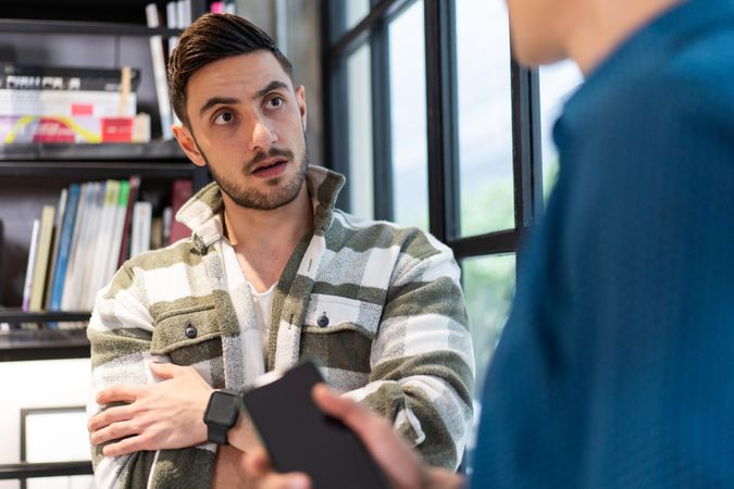 Two male colleagues discussing work project by office window