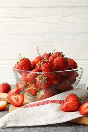 Composition with bowl of tasty strawberry on gray table. Summer berry