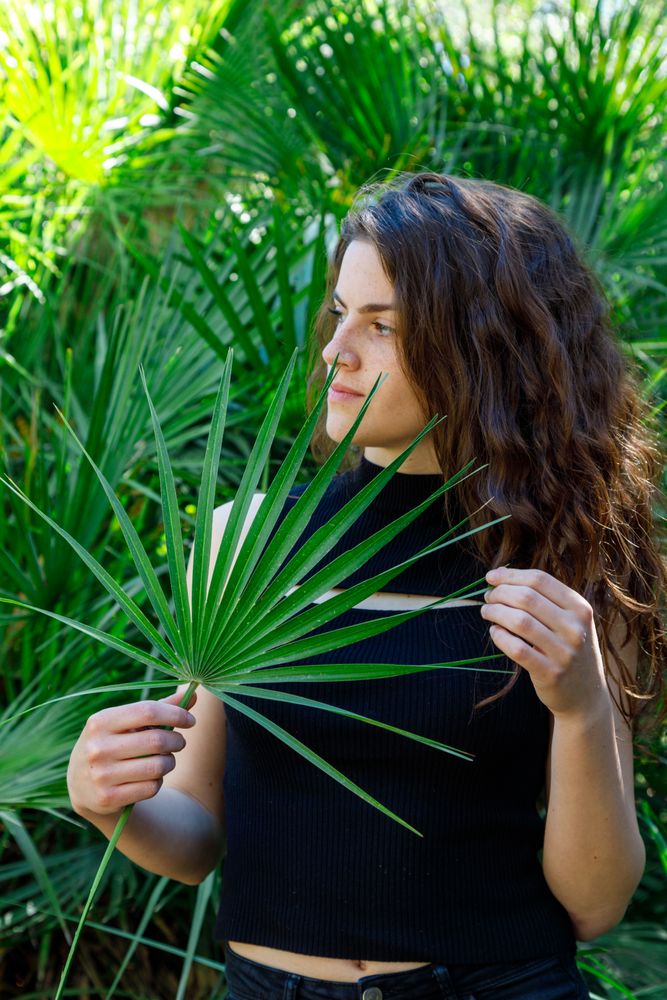 young female among green palm leaves