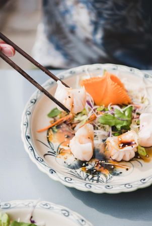 Man eating dumplings at Vietnamese restaurant with chopsticks