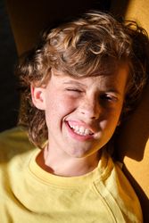 Smiling boy winking eye on sunny day