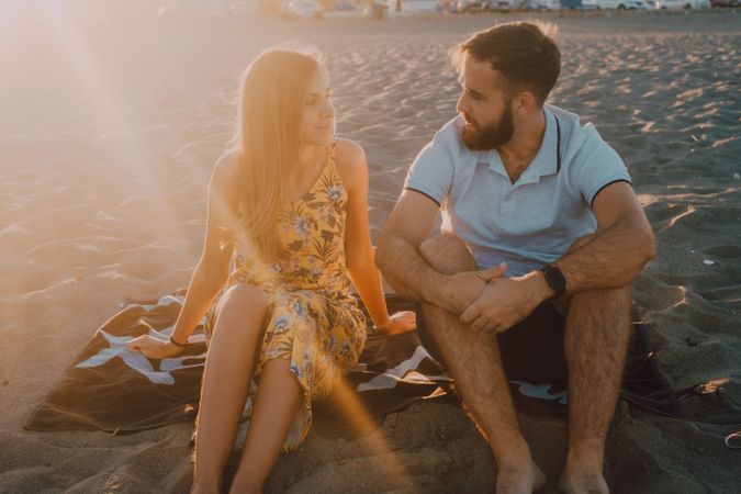 Tender couple talking and chilling in sunlight on towel beach