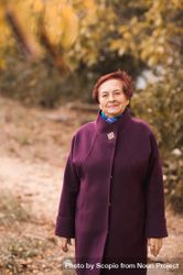 Older woman in purple coat standing near yellow trees 5kKBW5