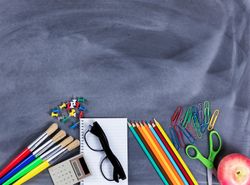 Back to school basic supplies placed on bottom part of erased chalkboard