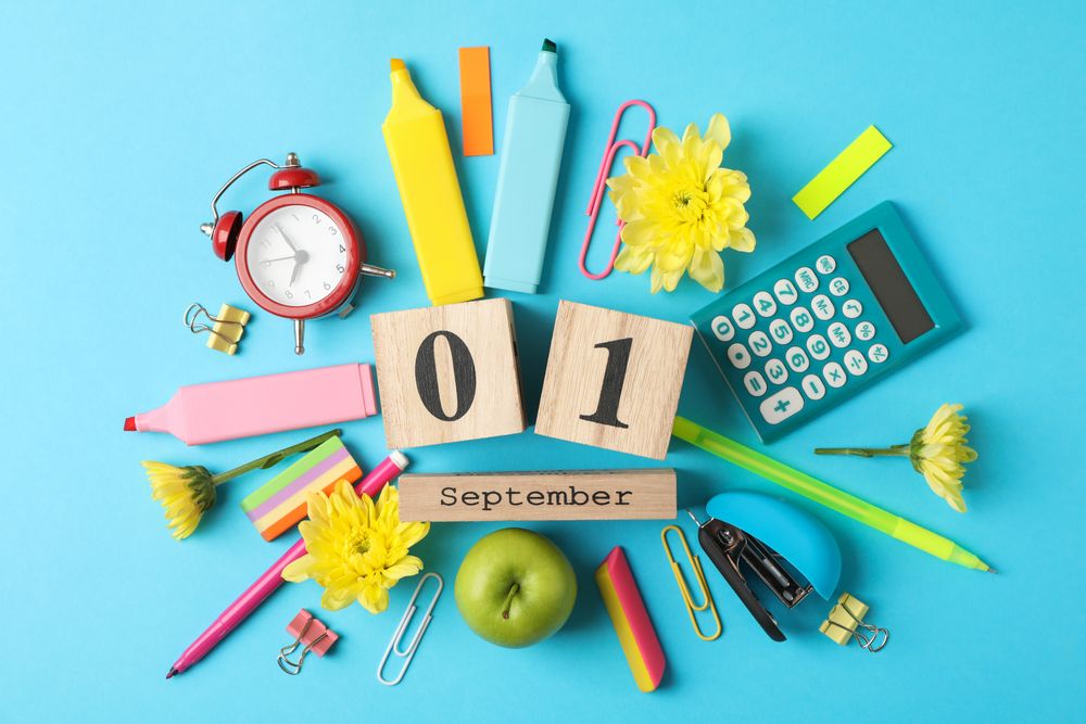 Wooden calendar with 1 september and school supplies on blue background