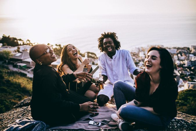 A group of friends laughing and hanging out overlooking the ocean