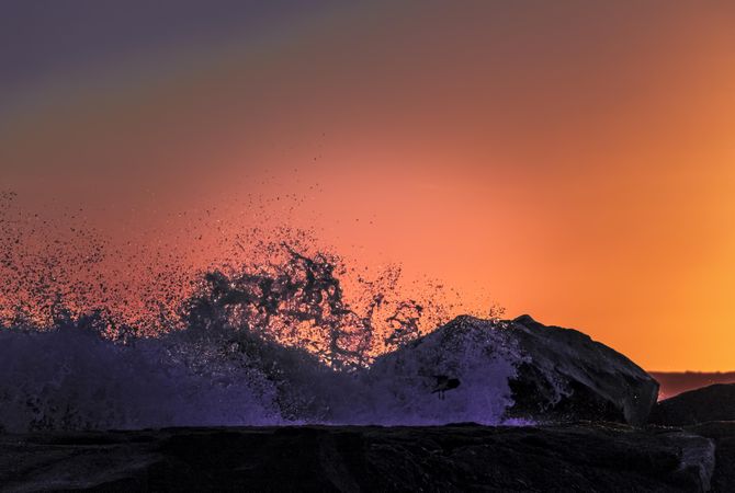 Close up of wave at it crashes with orange sky