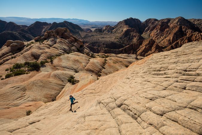 Person running down a rocky mountain during the day in Panguitch, UT , USA