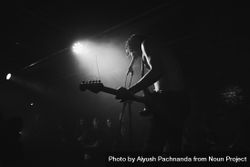 Young male rock musician singing on stage with guitar and spotlight bGRdX4