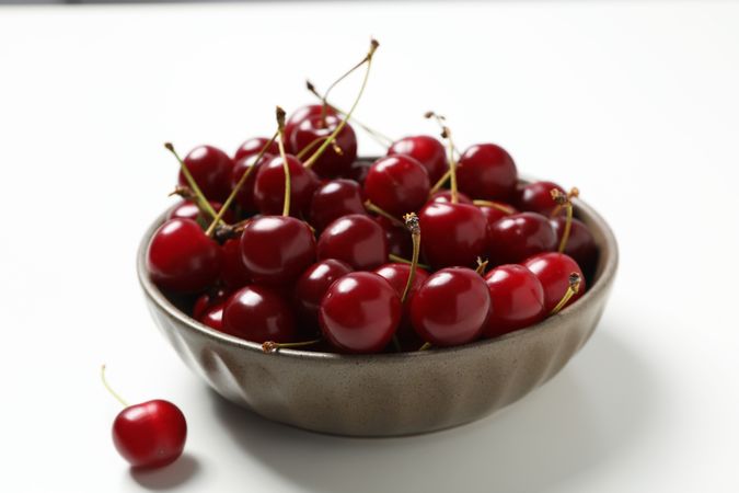 Ripe cherry fruits in a bowl on a light background