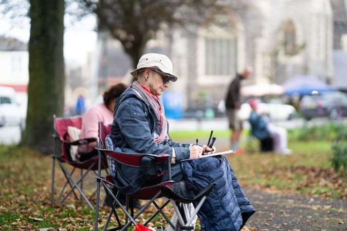 Side view of man sitting outside during drawing class