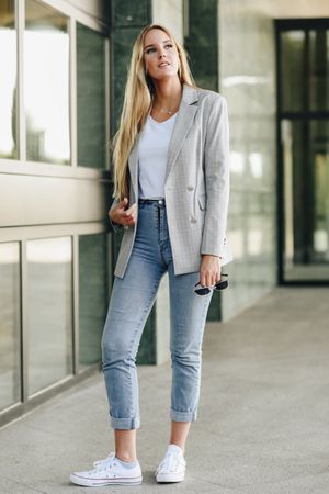 Serious woman in blazer standing outside offices