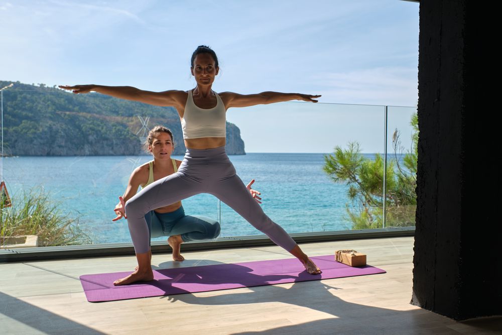 Sporty woman practicing Warrior pose with personal instructor