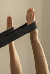 Close up of a woman's hands holding a yoga strap for an assisted stretching exercise.