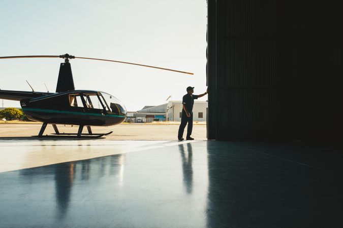 Man opening the door of the helicopter hangar