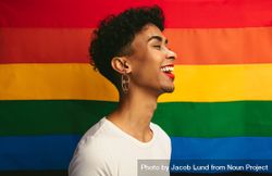 Smiling young man with make up standing against pride flag 5QPyV0