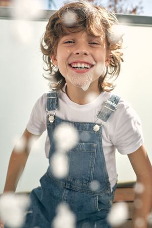 Cheerful boy playing with foam during cleaning
