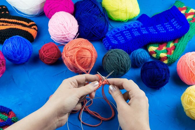 Woman knitting near colorful thread balls