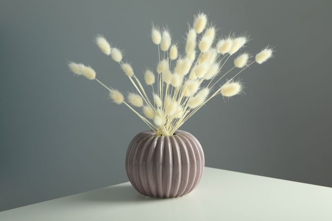Round and ridged vase in grey room filled with dried flowers