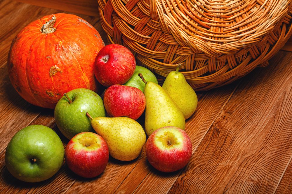 Autumnal fruit and squash on table with wicker basket