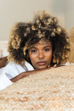 Thoughtful Black woman lying on bed in bedroom