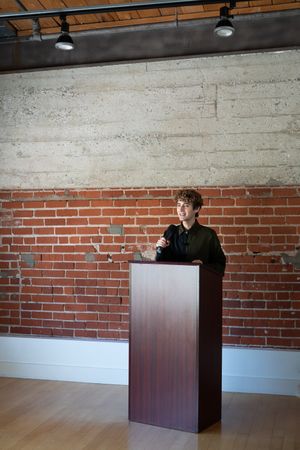Nonbinary person standing at podium with microphone
