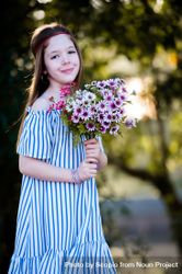 Smiling girl in blue striped dress holding a bouquet of flowers 4A8RR5