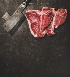 Two T-bone steaks with cleaver on butchers block with copy space