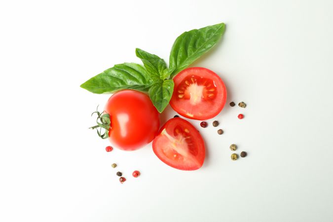 Fresh cherry tomatoes with basil and spices on plain background, space for text and top view. Ripe vegetables