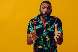 Serious male speaking at camera in brightly patterned shirt, copy space