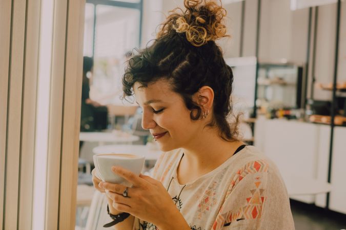 Positive woman drinking coffee in cafe