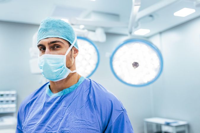 Portrait of medical professional wearing surgical mask and scrubs in operation theater