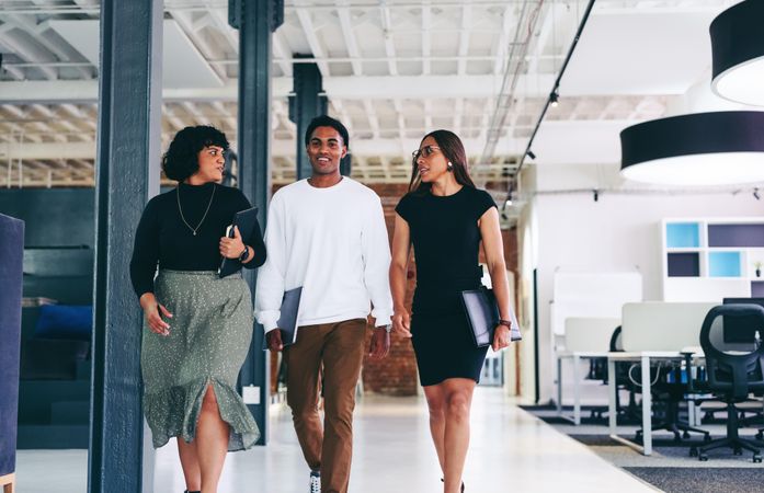 Three coworkers walking through modern office together