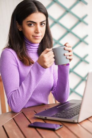 Female sitting on deck working on computer, vertical