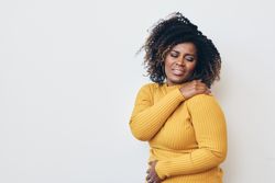 Black woman holding hand to her shoulder in pain