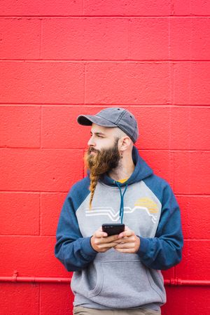 Man using smartphone near red wall