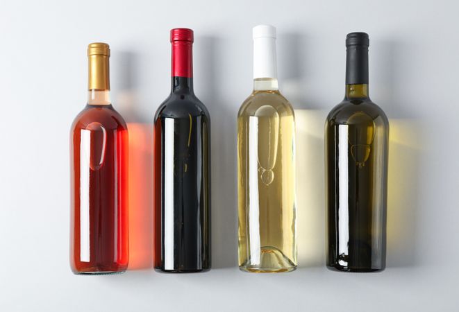 Bottles with different wine on grey background, top view