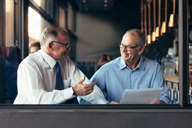 Mature businessman with male colleague working together in modern restaurant