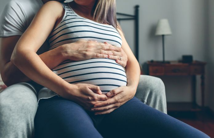Pregnant woman embraced by her husband