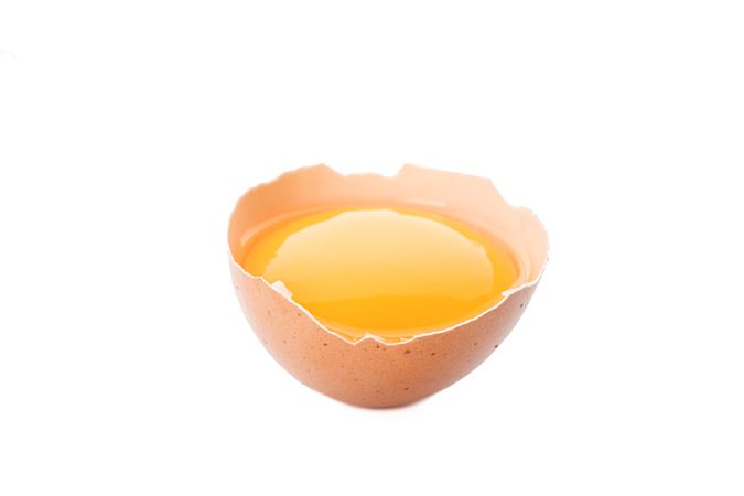 Half broken egg with yolk isolated on blank background