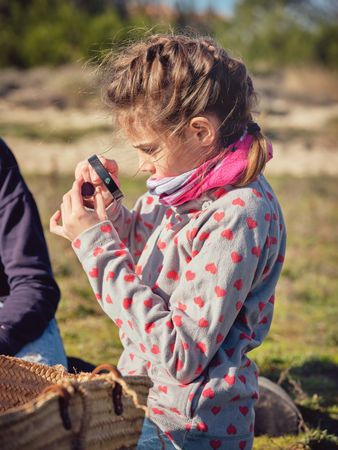 Adorable preteen girl looking at piece of plastic through magnif